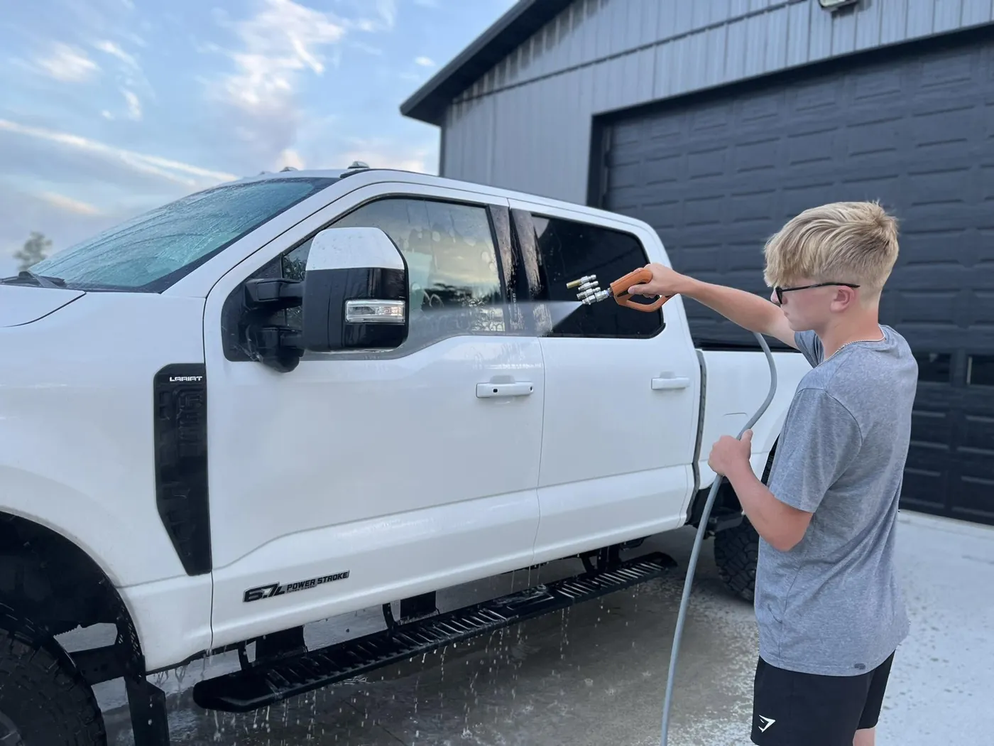 Landen rinsing a white Super Duty outside the shop.