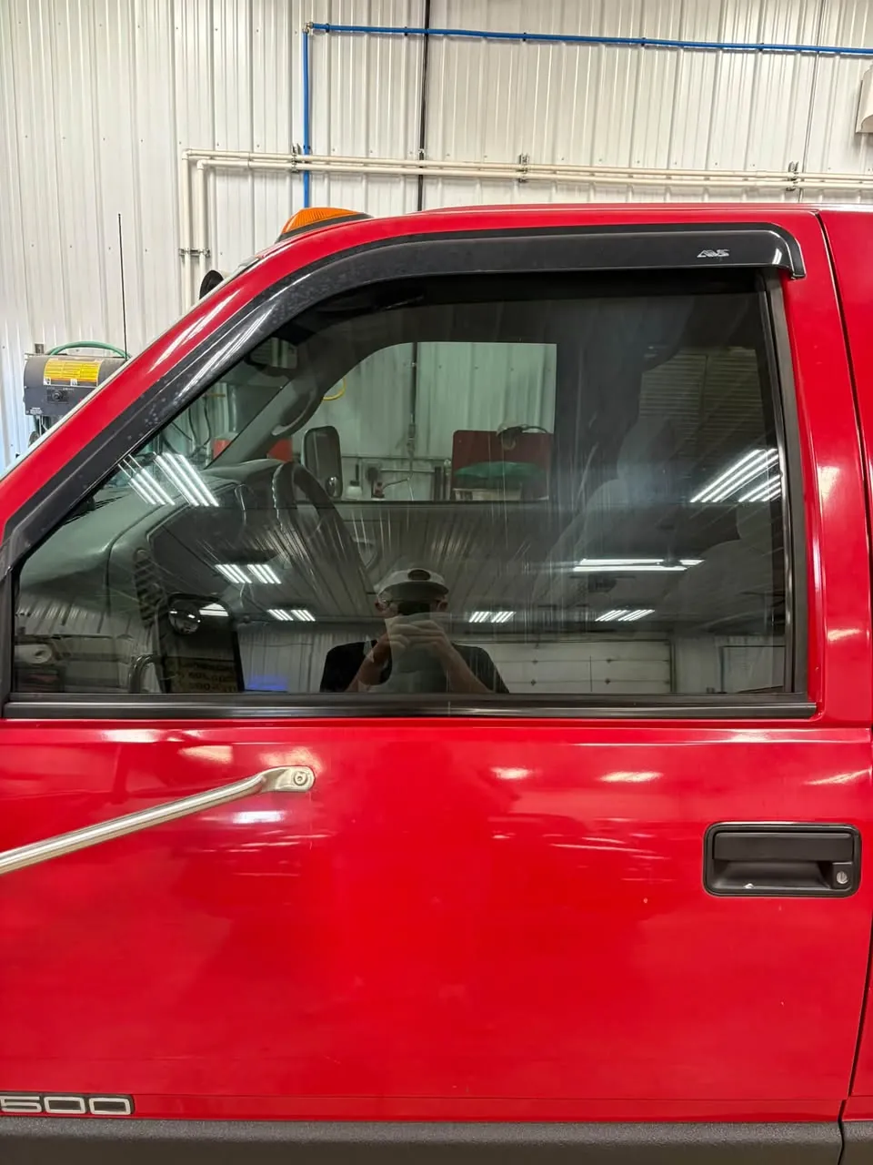 Red pickup with tinted rear door window, in the shop.